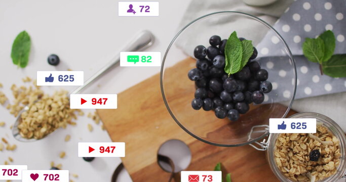Blueberry bowl resting beside granola jar in kitchen, with social media reaction icons, copy space - Powered by Adobe