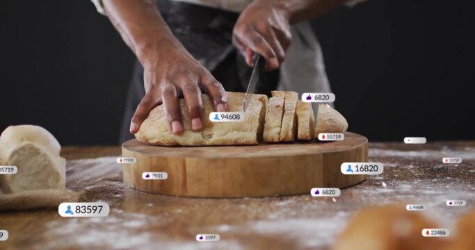 Cutting loaf baker wearing dark apron using knife on cutting board in kitchen, with reaction icons