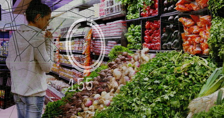 Browsing woman selecting carrots and peppers in produce aisle, with shopping basket, copy space