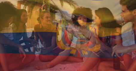 Chatting six friends sitting in loose circle on sandy beach at sunset, with beer bottles