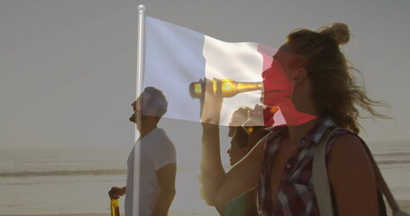 Walking friends holding beer bottles along sandy shoreline at golden hour, with French flag overlay