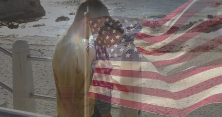 Walking couple gazing rocky shore from railing at waterfront walkway, with American flag overlay