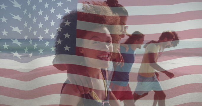 Walking friends in summer clothes laughing along shore, with ocean waves and American flag overlay - Powered by Adobe