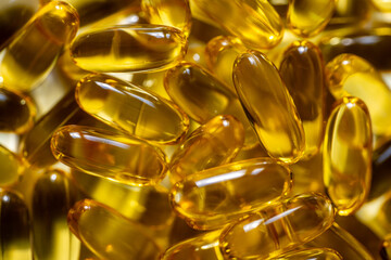 Golden transparent fish oil capsules close up. Dietary supplement and vitamin concept. Macro shot...
