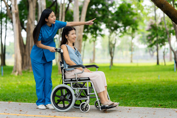 Caregiver takes elderly in wheelchair to walk in the park for health therapy, insurance concept for the elderly, happy retirement