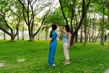 Asian female doctor takes care of elderly female patient in the park, helps the patient walk and exercises her legs and knees in the park.