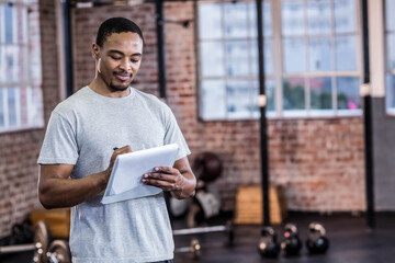 African American man holding tablet and stylus while tracking kettlebell workouts in brick gym