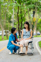 Caregiver takes elderly in wheelchair to walk in the park for health therapy, insurance concept for the elderly, happy retirement