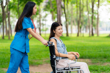 Caregiver takes elderly in wheelchair to walk in the park for health therapy, insurance concept for the elderly, happy retirement
