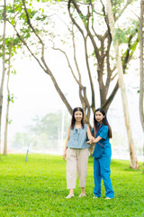 Asian female doctor takes care of elderly female patient in the park, helps the patient walk and exercises her legs and knees in the park.