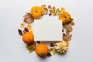 Autumn composition with paper blank and dried leaves with pumpkin on table. Flat lay, top view, copy space