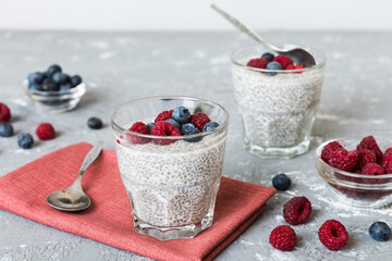 Healthy breakfast or morning with chia seeds vanilla pudding raspberry and blueberry berries on table background, vegetarian food, diet and health concept. Chia pudding with raspberry and blueberry