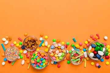 different colored round candy in bowl and jars. Top view of large variety sweets and candies with...