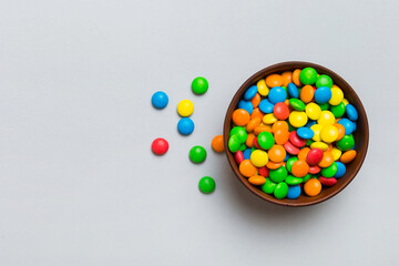 Multicolored candies in a bowl on a colored background. birthday and holiday concept. Top view with...