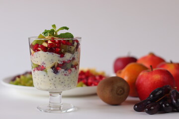 Chia seed pudding or chia custard in glass cups topped with pomegranate, kiwi, apple, and grapes