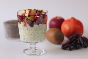 Chia seed pudding or chia custard in glass cups topped with pomegranate, kiwi, apple, and grapes