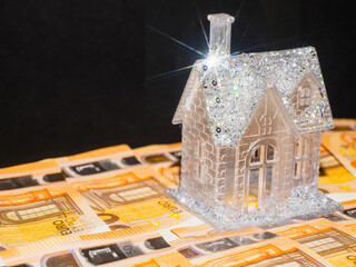 Premium glamourous house with glitter is standing on top of a flat surface covered cash money....