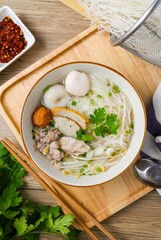 Clear pork noodle soup with thin rice noodles in ceramic bowl with chopsticks