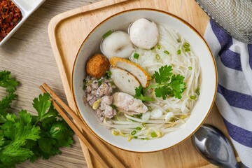 Clear pork noodle soup with thin rice noodles in ceramic bowl with chopsticks