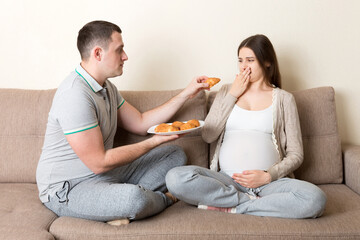 Husband offers croissants to his pregnant wife but she refuses and makes stop gesture because she...
