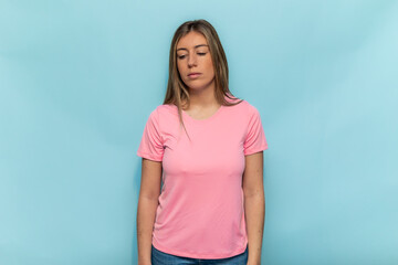 Sad woman wearing pink t-shirt for World Breast Cancer Day looking down