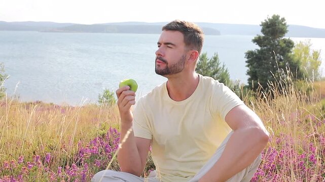 Video of healthy man eating an apple in nature 