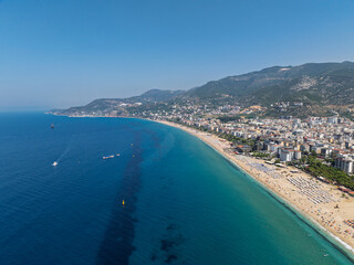 Fototapeta premium Aerial drone view of Cleopatra Beach in Alanya, Turkey. Alanya turquoise sea, sandy beach, cliffs, hills with caves, and the coastline during sunny summer day from above. Summer Mediterranean Sea.