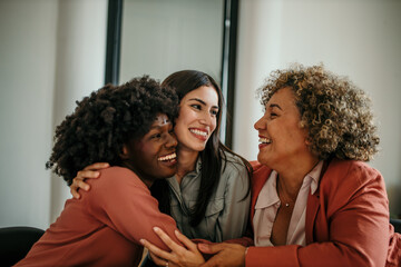 Happy businesswomen embracing and smiling in office environment