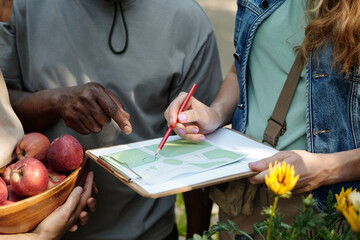 Young adult Caucasian woman holding clipboard with map, discussing directions with young adult...