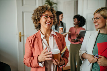 Businesswomen talking and smiling during coffee break in the office