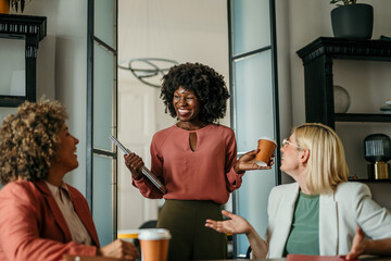 Smiling businesswomen having informal meeting while drinking coffee
