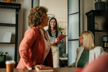 Smiling businesswoman entering meeting room holding folder