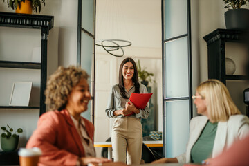 Smiling businesswoman entering meeting room holding folder