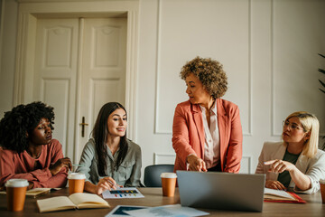 Businesswomen having meeting analyzing financial charts on laptop in office