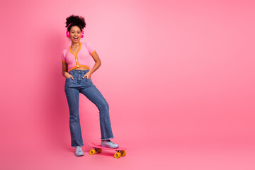 Fashionable young woman in pink outfit enjoying casual leisure time on skateboard with vibrant pink...