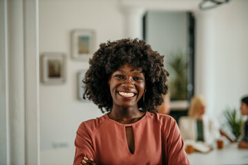 Young black businesswoman smiling with crossed arms in modern office
