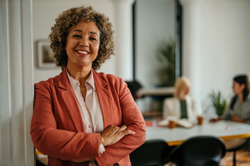 Smiling senior businesswoman posing with crossed arms in modern office