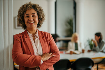 Smiling senior businesswoman posing with crossed arms in modern office