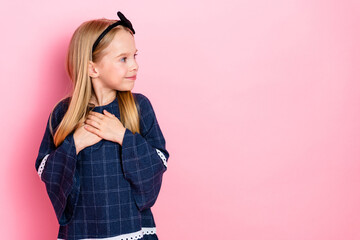 Charming young girl in a trendy outfit smiling and looking away on a vibrant pink background,...