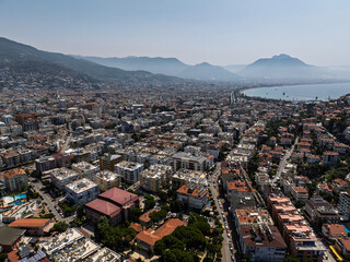 Aerial view of Alanya city in Turkey. Dense urban buildings, Mediterranean coastline, green hills...