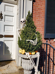 Skeletons and pumpkins on the doorstep of a house decorated for Halloween.