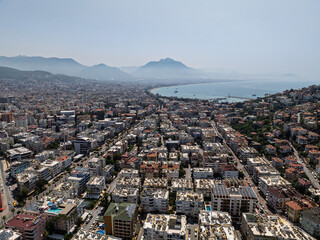 Aerial view of Alanya city in Turkey. Dense urban buildings, Mediterranean coastline, green hills...