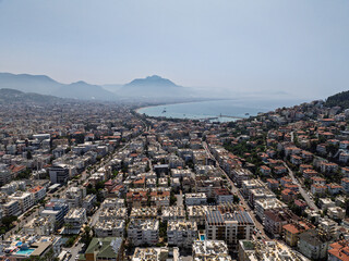 Aerial view of Alanya city in Turkey. Dense urban buildings, Mediterranean coastline, green hills...