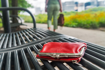 woman left her red wallet with money on a park bench.
