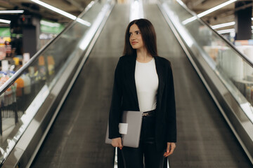 Professional Woman With Laptop on an Escalator in a Modern Building