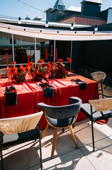 Elegant outdoor dining setup with red decor and floral arrangements on a sunny day