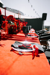 Elegant outdoor dining setup with red and black decor for a special event at sunset