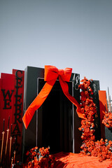 Festive entrance decorated with red flowers and a large bow for a celebration event