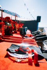 Elegant outdoor dining setup with red decor and glassware on a sunny day