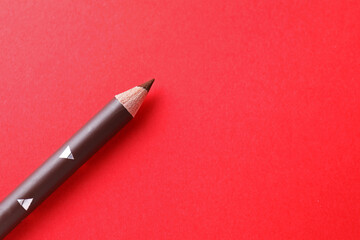One eyebrow pencil on red background, top view. Space for text